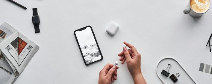 Flat lay of a modern workspace featuring tech devices, a latte, and office supplies.