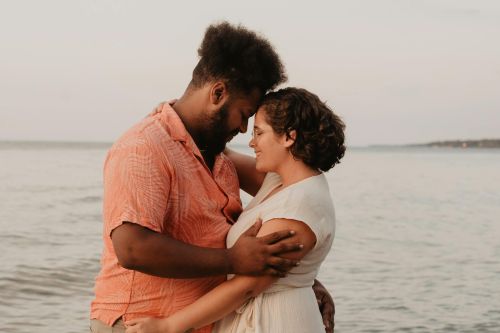 A loving couple embraces on the beach at sunset, showcasing warmth and romance.