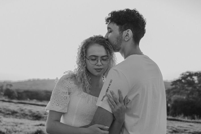 Young couple sharing a tender moment outdoors, captured in black and white.